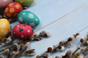Obraz premium Willow and easter painted eggs lie on a blue background
