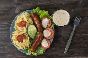 Macaroni, vegetables and fried sausages with dark beer, top