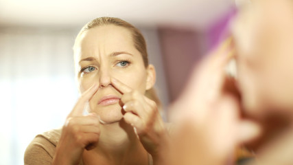 the girl looks in the mirror, dissatisfied with the appearance, pulls the skin. Ugly, aging skin. Allergy to cosmetics, fear of aging, circles under the eyes, wrinkles. Low self-esteem, dysmorphic dis