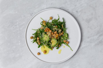 Quinoa salad on white plate on marble table