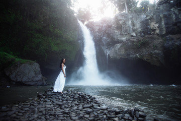 Happy woman near big waterfall traveling at Bali, Ubud. Summer