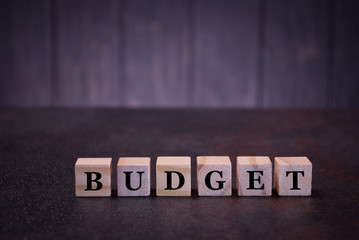 The word budget on wooden cubes, on a dark background, symbols signs