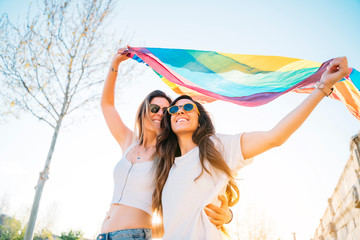 Couple lesbian woman with gay pride flag on the street