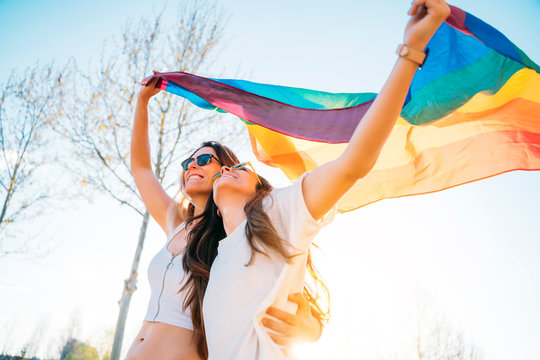 Couple lesbian woman with gay pride flag on the street