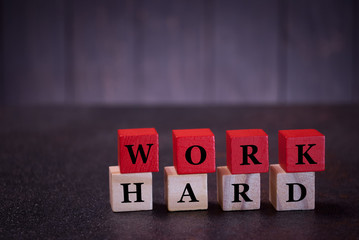 The word work hard on wooden cubes, on a dark background, symbols signs