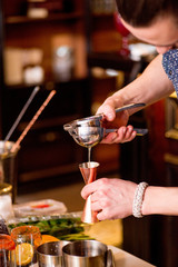 barman preparing cocktail, pours liquid into the jigger in a cocktail bar