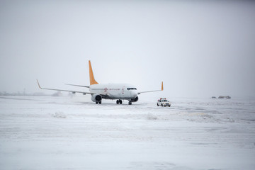 Airliner on runway in blizzard. Aircraft during taxiing on landing strip during heavy snow....