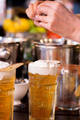 female bartender preparing cocktail in a cocktail bar and decorates the finished drink in a glass