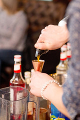 Bartender pours liquid into the jigger. Female bartender preparing cocktail in a cocktail bar