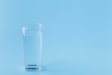 Clear water in glass cup on blue