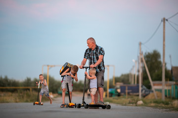 large family is riding scooter along village street. concept of a sports family. © galitsin