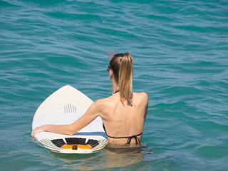girl with a surfboard comes into the ocean.