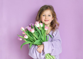 Beautiful girl holding a bouquet of tulip flowers on a light background. Mother's day or Woman's...