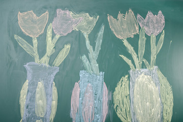 Children's chalk drawing of tulips on a blackboard