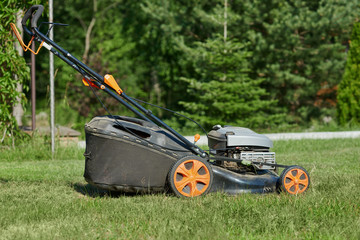 The mower on the green lawn near the countryside cottage.