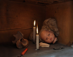 Cabeza de muñeca de niña en un altar de madera con velas rojas y blancas, vértebras y dientes de vaca, un sapo muerto disecado - obrazy, fototapety, plakaty