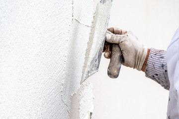 Construction worker plastering and smoothing concrete wall with cement
