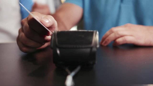 Man fails to pay for his purchase via passing his card through the terminal on a counter. Close up view focus on a bank terminal. Non-cash payment, electronic chip, card reader. Failure, stress