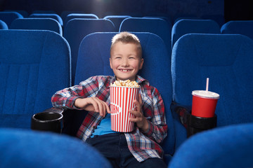 Joyful kid laughing, watching comedy film in cinema.