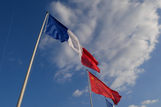 French and Chinese flags with clouds and blue sky, Paris