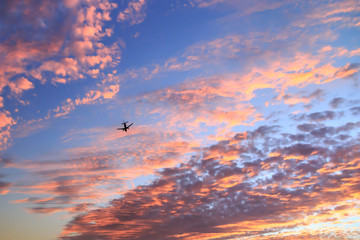 Airplane flying in the cloudy sunset sky. Travel transport airline sky background concept. Copy space.