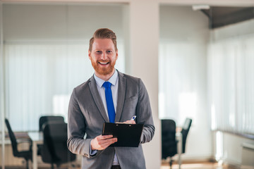 Young entrepreneur writing on notepad while standing in office.