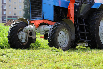 tractor that mows grass on urban lawns. the tractor mows the grass with a special attachment mower with circular knives. wheels close up.