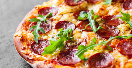 Pepperoni Pizza with Mozzarella cheese, salami, Tomato sauce, pepper, Spices and Fresh arugula. Italian pizza  on Dark grey black slate background
