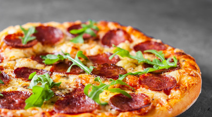 Pepperoni Pizza with Mozzarella cheese, salami, Tomato sauce, pepper, Spices and Fresh arugula. Italian pizza  on Dark grey black slate background