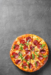 Pepperoni Pizza with Mozzarella cheese, salami, Tomato sauce, pepper, Spices and Fresh arugula. Italian pizza  on Dark grey black slate background