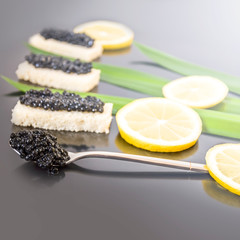  black caviar on bread and a spoon, green leaves