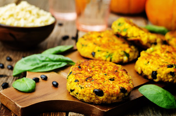 black bean millet pumpkin burgers with spinach leaves on a wood background