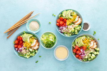 Lunch bowls with grilled cgicken meat, rice and fresh salad of avocado, cucumbers, corn, tomato and onion