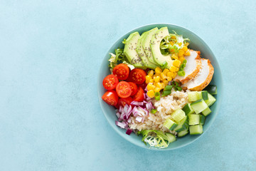 Lunch bowls with grilled cgicken meat, rice and fresh salad of avocado, cucumbers, corn, tomato and...