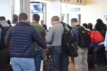 A large crowd of travelers wait at their gate for an incoming flight at RDU International airport. 