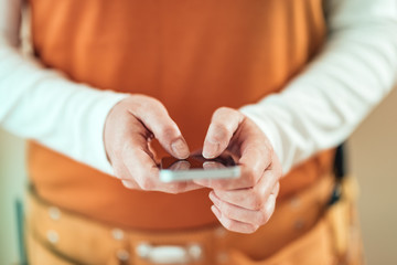 Female carpenter is using mobile phone for text messaging