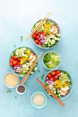 Lunch bowls with grilled cgicken meat, rice and fresh salad of avocado, cucumbers, corn, tomato and onion