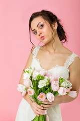 beautiful bride with wedding bouquet of pink tulips on pink background