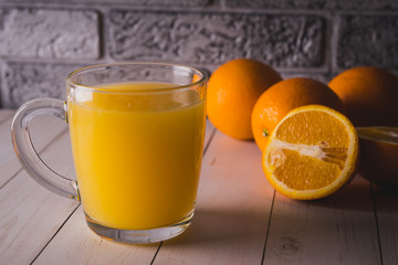 Glass of freshly squeezed orange juice standing on light background with a fresh oranges.  Healthy lifestyle concept