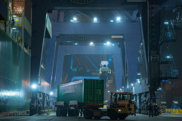 operation of container terminal at night. Unloading container ship at night. Mooring cranes unload...