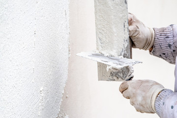 Construction worker plastering and smoothing concrete wall with cement