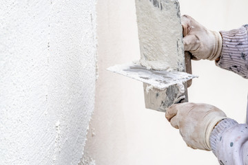 Construction worker plastering and smoothing concrete wall with cement
