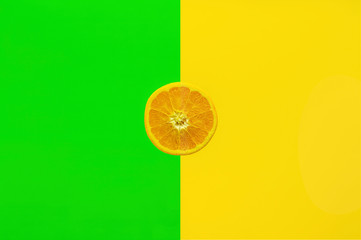 Orangenscheibe, halb aufgeschnittene Orange vor farbigem Hintergrund halb in kräftigem grün und gelb
