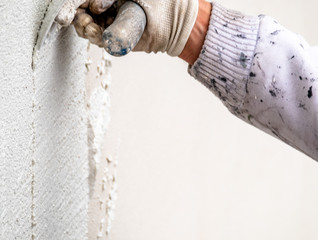 Construction worker plastering and smoothing concrete wall with cement