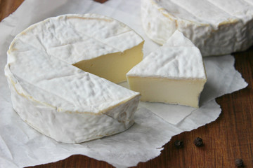 Camembert cheese. Farm products, rustic cheese. Natural cheese, round head of cheese with Camembert mold, cut on a wooden Board surrounded by fragrant spices. Cheese plate for gourmets.