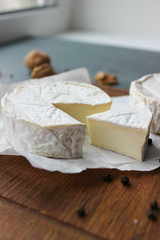 Camembert cheese. Farm products, rustic cheese. Natural cheese, round head of cheese with Camembert mold, cut on a wooden Board surrounded by fragrant spices. Cheese plate for gourmets.