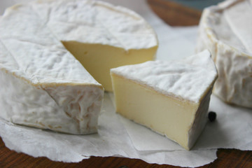 Camembert cheese. Farm products, rustic cheese. Natural cheese, round head of cheese with Camembert mold, cut on a wooden Board surrounded by fragrant spices. Cheese plate for gourmets.