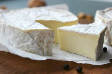 Camembert cheese. Farm products, rustic cheese. Natural cheese, round head of cheese with Camembert mold, cut on a wooden Board surrounded by fragrant spices. Cheese plate for gourmets.