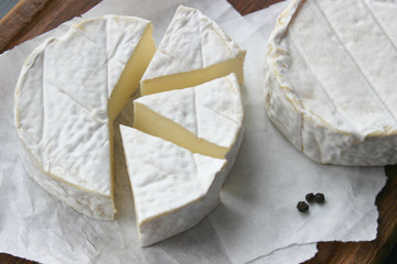 Camembert cheese. Farm products, rustic cheese. Natural cheese, round head of cheese with Camembert mold, cut on a wooden Board surrounded by fragrant spices. Cheese plate for gourmets.
