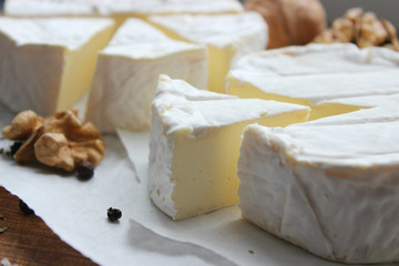 Camembert cheese. Farm products, rustic cheese. Natural cheese, round head of cheese with Camembert mold, cut on a wooden Board surrounded by fragrant spices. Cheese plate for gourmets.